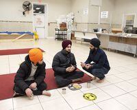 International students Gursharanpreet Singh, left, and Anmol Singh, centre, speak with Harmanpreet Singh while eating dinner inside of the langar hall in the Gurdwara Sikh Sangat in Brampton, ON on December 22nd, 2021 - Duane Cole/The Globe and Mail