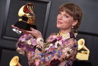 Taylor Swift poses in the press room with the award for album of the year for "Folklore" at the 63rd annual Grammy Awards at the Los Angeles Convention Center on Sunday, March 14, 2021.