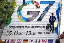 People goes down station stairs featuring the logo of the G7 Finance Ministers and Central Bank Governors meeting, in Niigata, Japan, Wednesday, May 10, 2023. The G7 Niigata is scheduled on May 11-13. (AP Photo/Shuji Kajiyama)