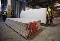 Construction workers move sheets of drywall at a building project in Calgary, Alta., Friday, Dec. 30, 2016.&nbsp;Statistics Canada says wholesale sales fell 0.7 per cent in February to $68.8 billion, the second drop in three months. The agency says sales were lower in four of the seven subsectors, led by building material and supplies, and motor vehicle and motor vehicle parts and accessories. THE CANADIAN PRESS/Jeff McIntosh
