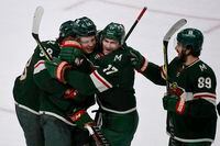 Minnesota Wild Joel Eriksson Ek, second from left, celebrates with right wing Ryan Hartman, left, left wing Marcus Foligno (17) and center Frederick Gaudreau (89) after Eriksson Ek scored against the Vancouver Canucks in overtime during an NHL hockey game Thursday, March 24, 2022, in St. Paul, Minn. The Wild won 3-2. (AP Photo/Craig Lassig)