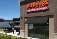 A worker carries garbage to a bin as construction takes place on Popeyes Louisiana Kitchen restaurant in Bowmanville, Ont. on June 3, 2017.