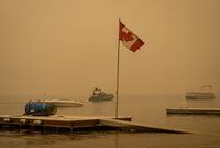 A large majority of Canadians are worried about climate change and believe it is behind an increase in extreme weather a new national poll suggests. Thick smoke from the Lower East Adams Lake wildfire fills the air and a Canadian flag flies in the wind as RCMP officers on a boat patrol Shuswap Lake, in Scotch Creek, B.C., on Sunday, August 20, 2023. THE CANADIAN PRESS/Darryl Dyck