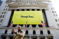 A man takes a photograph of the front of the New York Stock Exchange (NYSE) with a Snap Inc. logo hung on the front of it shortly before the company's IPO in New York, U.S., March 2, 2017.