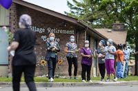 Staff gather outside the Orchard Villa retirement home to watch people lay flowers at an event to honour victims of COVID-19, on June 1, 2020.