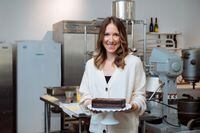 Dara Sutin, a chef and food stylist, poses for a portrait with a cake made by Jill Barber, owner of new bakery Barbershop Patisserie, in Toronto, Thursday, December 17, 2020. Sutin has produced an online cookbook featuring recipes from 34 chefs, with proceeds going to benefit a non-profit that offers mental health services to people in the food industry. Barber contributed the recipe for a chocolate fudge cake with chocolate pudding ganache, pictured. (Galit Rodan/The Globe and Mail)