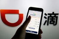 FILE PHOTO: The app of Chinese ride-hailing giant Didi is seen on a mobile phone in front of the company logo displayed in this illustration picture taken July 1, 2021. REUTERS/Florence Lo/Illustration/File Photo