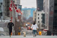 A jogger keeps his distance from a woman walking her dog in downtown Toronto, Ontario on March 24, 2020. - The province of Ontario has set a deadline of midnight Tuesday for all non-essential businesses to close due to the Covid-19 outbreak. Prime Minister Justin Trudeau's online plea for people to stay home during the coronavirus pandemic has gone viral, with actor Ryan Reynolds, musician Michael Buble and other Canadian celebrities on Tuesday helping to spread the word. (Photo by Geoff Robins / AFP) (Photo by GEOFF ROBINS/AFP via Getty Images)