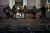 Climate protestors hold a vigil on the steps of the Royal Exchange, near the Bank of England in London, England, Friday, Oct. 29, 2021. People protested in London ahead of the 26th U.N. Climate Change Conference (COP26), which starts Sunday in Glasgow, Scotland. (AP Photo/Frank Augstein)