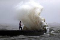 A wave crashes as a man stands on a jetty near Orleans Harbor in Lake Pontchartrain in New Orleans on June 7, 2020, as Tropical Storm Cristobal approaches the Louisiana Coast. The storm is now on its way to Canada.