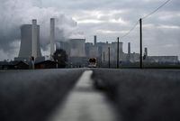 (FILES) In this file photo taken on January 17, 2022 a bus drives on a road as steam rises from the cooling towers of the lignite-fired power plant of German energy giant RWE in Niederaussem, western Germany. - Germany said on June 20, 2022 it still aimed to close its coal power plants by 2030, despite a recent decision to revert to the fuel in the midst of an energy crisis provoked by Russia's invasion of Ukraine. "The 2030 coal exit date is not in doubt at all. It is more important than ever that it is realised in 2030," economy ministry spokesman Stephan Gabriel Haufe said at a regular press conference. (Photo by Ina FASSBENDER / AFP) (Photo by INA FASSBENDER/AFP via Getty Images)