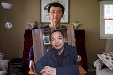 Sophie Luo Shengchun, the wife of jailed Chinese human rights lawyer, Ding Jiaxi, poses with a photo of him at her home in Alfred, New York, U.S., July 28, 2022. REUTERS/Brendan McDermid