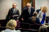 FILE PHOTO: Greg McMichael and his son, Travis McMichael, look at family members seated in the gallery when they walk into the courtroom for the reading of the jury's verdict in the trial over Ahmaud Arbery's killing, in the Glynn County Courthouse, in Brunswick, Georgia, U.S., November 24, 2021. Stephen B. Morton/Pool via REUTERS/File Photo