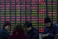 Investors stand in front of an electronic board showing stock information on the first trading day after the week-long Lunar New Year holiday at a brokerage house in Shanghai, China, February 15, 2016.
