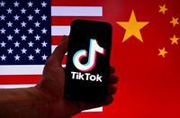 In this photo illustration the social media application logo for TikTok is displayed on the screen of an iPhone in front of a US flag and Chinese flag background in Washington, DC, on March 16, 2023. - China urged the United States to stop "unreasonably suppressing" TikTok on March 16, 2023, after Washington gave the popular video-sharing app an ultimatum to part ways with its Chinese owners or face a nationwide ban. (Photo by OLIVIER DOULIERY / AFP) (Photo by OLIVIER DOULIERY/AFP via Getty Images)