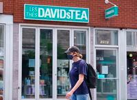 A woman wearing a protective mask walks past a closed DavidsTea store in Montreal on Wednesday, July 8, 2020. Insolvent beverage retailer DavidsTea is closing 82 stores in Canada and exiting the U.S. market as it focuses on its e-commerce business and supplying grocery stores and pharmacies. THE CANADIAN PRESS/Paul Chiasson
