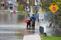 Local residents make their way to dry land following flooding in the Gatineau region of Quebec on Thursday, May 4, 2023. The Insurance Bureau of Canada says more than 1.5 million households in Canada are “highly exposed” to flood risk. THE CANADIAN PRESS/Spencer Colby