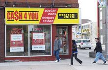 People walk pass a pay day loan store in Oshawa, Ont., on May 13, 2017. Payday lenders in Canada are increasingly being pinched by regulations as more municipalities look to impose restrictions on their business activities and rein in the number of physical locations. Toronto is the latest municipality to crack down on payday lenders with new regulations that cap the number of physical locations allowed across the city and require operators to be licensed and pay a fee. THE CANADIAN PRESS/Doug Ives
