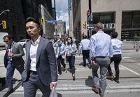 Pedestrians crossing Wellington St. West by Bay St. in Toronto’s Financial District are photographed on July 12, 2022. Fred Lum/The Globe and Mail. 