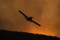 A small aircraft is pictured after dumping fire retardant behind houses at the foot of Mount Tennant, in Canberra, Australia, on Jan. 30, 2020.