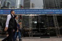 People walk past an electronic sign displaying stocks at Exchange Square in Hong Kong on March 16.
