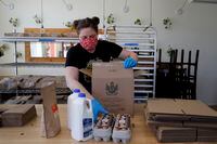 Monica Mileur packs grocery items into a box at Union Loafers restaurant Friday, April 10, 2020, in St. Louis. Some restaurants have turned to selling groceries and other provisions to customers as a way to help make up for revenue lost during the coronavirus outbreak. (AP Photo/Jeff Roberson)