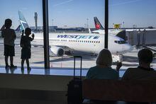 Young boys look out at Air Canada and WestJet planes at Calgary International Airport in Calgary, Alta., Wednesday, Aug. 31, 2022. WestJet announces its first flight to Asia in a plan to expand Calgary's airport capacity by over 25 per cent by next year. THE CANADIAN PRESS/Jeff McIntosh