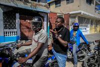 Jimmy Cherizier, the leader of the "G9 et Famille" gang talks with members of his gang while taking a ride on the back of a motorcycle, in his neighborhood of Delmas 6, a district of Port-au-Prince, Haiti, Tuesday, Jan. 24, 2023. Cherizier, best known by his childhood nickname Barbecue, has become the most recognized name in Haiti. (AP Photo/Odelyn Joseph)