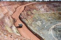 A dump truck loaded with ore drives along a haul road in the open pit mine at Zijin mining operation in Australia.