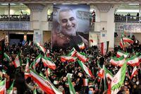 Iranians lift national flags during a ceremony in the capital Tehran, on January 3, 2022, commemorating the second anniversary of the killing in Iraq of top Iranian commander Qasem Soleimani (portrait) and Iraqi commander Abu Mahdi al-Muhandis in a US raid. (Photo by ATTA KENARE / AFP) (Photo by ATTA KENARE/AFP via Getty Images)