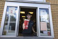 An employee at a Tim Hortons hands out a coffee from their drive-thru window with a hand-made sign saying  "The whole world is in need of employees- be nice to those who have returned to work" in St-Bruno-de-Montarville, Quebec, September 29, 2022.   (Christinne Muschi /The Globe and Mail)