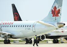 Airline ground crew walks past grounded Air Canada planes as they sit on the tarmac at Pearson International Airport, in Toronto on Tuesday, April 27, 2021.