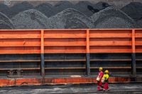 Workers walk near a tugboat carrying coal barges at a port in Palembang, South Sumatra province, Indonesia, on Jan. 4.