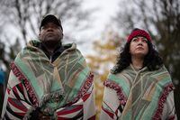 Sgt. Michael Wilson, left, husband of Tsleil-Waututh Chief Leah George-Wilson, a U.S. Army veteran from New Convert, Ala., who served in the Gulf War stands beside Pfc. Celina Dorame, a Tsleil-Waututh Nation member who was born in California and served with the U.S. Army, wearing blankets as they listen during a ceremony held by the First Nation to mark Indigenous Veterans Day, in North Vancouver, B.C., Monday, Nov. 8, 2021. Veterans Affairs Canada estimates that more than 12,000 First Nations, Inuit and Metis served during the First and Second World Wars and the Korean War. THE CANADIAN PRESS/Darryl Dyck