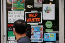 FILE PHOTO: A pedestrian passes a "Help Wanted" sign in the door of a hardware store in Cambridge, Massachusetts, U.S., July 8, 2022.   REUTERS/Brian Snyder