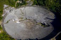 This aerial view shows the damage at the Arecibo Observatory after one of the main cables holding the reciever broke in Arecibo, Puerto Rico, on December 1, 2020. - The radio telescope in Puerto Rico, which once starred in a James Bond film, collapsed Tuesday when its 900-ton receiver platform fell 450 feet (140 meters) and smashed onto the radio dish below. (Photo by Ricardo ARDUENGO / AFP) (Photo by RICARDO ARDUENGO/AFP via Getty Images)