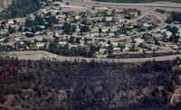 A road separates homes from an area burned by wildfire in the Glenrosa area of Kelowna, B.C., on Tuesday July 21, 2009. Six thousand of the 11,000 evacuated Kelowna area residents were allowed to return home Tuesday morning. THE CANADIAN PRESS/Darryl Dyck
