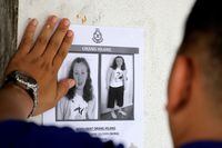A police officer pastes a photo of 15-year-old Nora Anne Quoirin on a wall at a shop in Seremban, Malaysia, on Aug. 9, 2019.