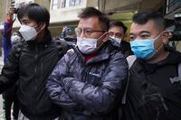 Senior editor of "Stand News" Ronson Chan, center, is arrested by police officers in Hong Kong, Wednesday, Dec. 29, 2021. Hong Kong police said they arrested several of its staff, including Chan, who is also head of the Hong Kong Journalists Association, early Wednesday morning for conspiracy to publish a seditious publication. (AP Photo)
