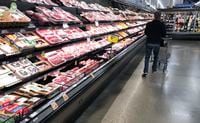 FILE - In this May 10, 2020 file photo, a shopper pushes his cart past a display of packaged meat in a grocery store in southeast Denver. U.S. wholesale prices edged up a slight 0.1% in November 2020 as weak demand caused by the pandemic has kept inflation at extremely low levels. (AP Photo/David Zalubowski, File)