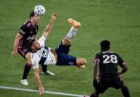 Vancouver Whitecaps forward Lucas Cavallini, centre, does a bicycle kick in front of Seattle Sounders defender Yeimar Gomez, right, in Portland, Ore., on Oct. 27, 2020. Seattle won 2-0.
