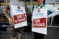 As Metro workers at 27 grocery stores in the Greater Toronto Area go back to work after a month-long strike, experts and union representatives say their new collective agreement will help raise the bar for grocery store workers across the country. Workers hold signs at a picket line outside a Metro grocery store in Toronto, Saturday, July 29, 2023. THE CANADIAN PRESS/Cole Burston