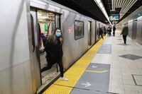 A woman wearing a mask exits a subway train in Toronto, on March 17, 2020.