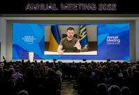 FILE - Ukrainian President Volodymyr Zelenskyy is seen on a screen as addresses the audience from Kyiv during the World Economic Forum in Davos, Switzerland, Monday, May 23, 2022. Ukraine's president said Wednesday, May 25, 2022 that Russia must pull back to its pre-war positions as a first step before diplomatic talks, a negotiating line that Moscow is unlikely to agree to anytime soon. (AP Photo/Markus Schreiber, File)