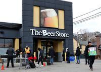 People line up in a parking lot for a long wait to return empties or buy beer at a Beer Store in downtown Toronto on April 16, 2020.