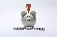 The letter dice TFSA VS RRSP resting in front of a white ceramic piggybank. The piggybank has a 50 dollar banknote inserted into its slot. 