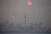 The sun rises through a cover of wildfire smoke above the CN Tower and downtown skyline in Toronto, Ontario, Canada July 20, 2021.  REUTERS/Carlos Osorio     TPX IMAGES OF THE DAY