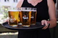 A bar worker carries a tray of Carlsberg beer in Copenhagen, Denmark, July 30, 2022. REUTERS/Andrew Kelly/Files