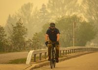Sean Myers rides his bike wearing a mask to protect himself from the smoke while Calgary is covered under a blanket of smoke from the forest fires in northern Alberta, May 16, 2023.  Todd Korol/The Globe and Mail