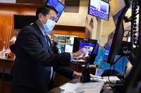 In this photo provided by the New York Stock Exchange, trader Mark Muller works in his booth on the floor, Thursday, Feb. 3.